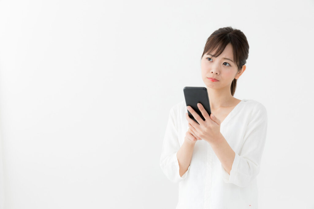 スマホを持ち首を傾げる女性