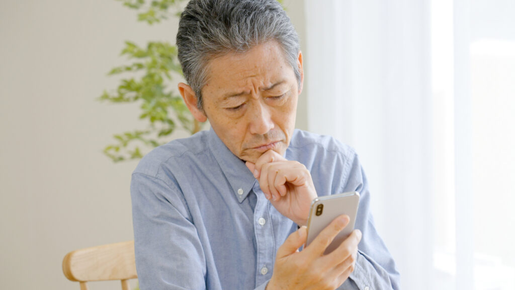 スマホを見て考え込む男性