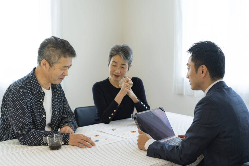 スーツの男性から説明を受けるシニア夫婦